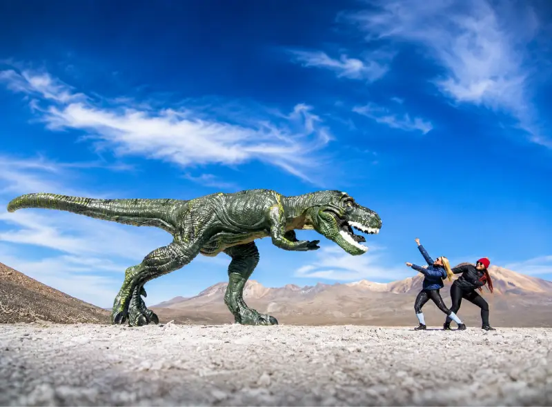 Visitantes junto a una figura de dinosaurio durante una excursión al Salar de Salinas desde Arequipa