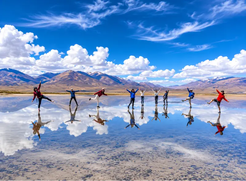 Viajeros tomando fotografías con reflejos de agua en el Salar de Salinas en Arequipa