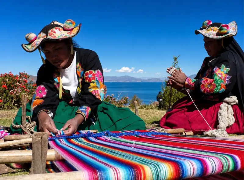 Mujeres con vestimenta tradicional y textiles durante una experiencia cultural en el Lago Titicaca